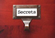 Shocking Tattoo — Democratic Candidate’s Dark Secret A label holder on a wooden surface with the word Secrets displayed