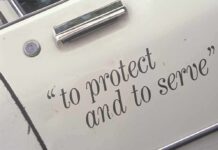 Close-up of a police car door with the phrase to protect and to serve