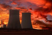 Russia Holds Largest NUCLEAR Plant HOSTAGE—Millions at Risk Silhouette of cooling towers against a vibrant sunset sky