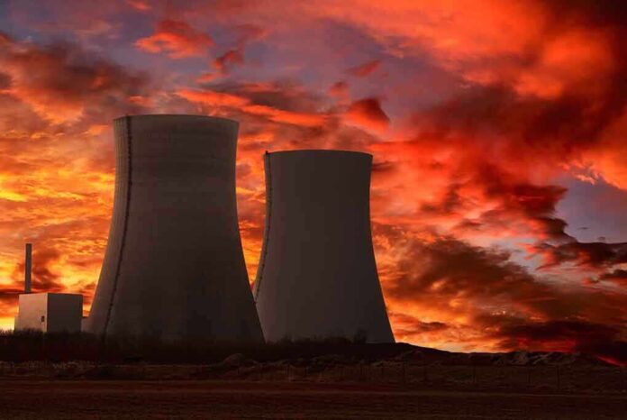 Silhouette of cooling towers against a vibrant sunset sky