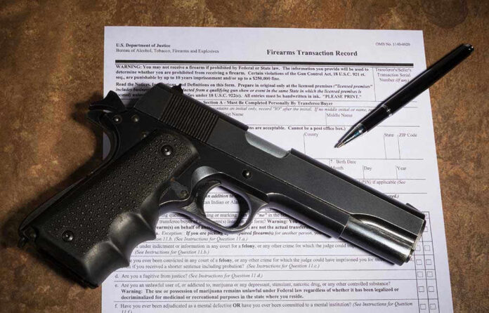 Gun and pen on firearm transaction form.
