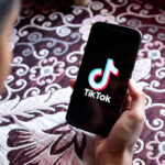 Hand holding phone showing TikTok logo