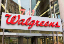 Walgreens store entrance sign with city reflections.