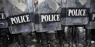 Police officers in riot gear holding shields.