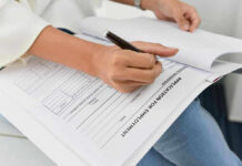 Banks Demands OPT Shutdown—US Students REJOICE Person filling out job application form.