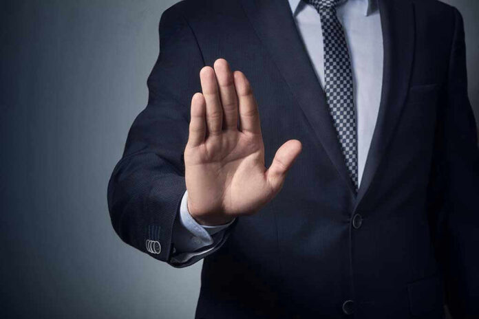 611111144 Man in suit with hand raised, signaling stop.