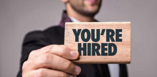 Person holding a Youre Hired sign.