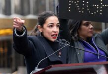 Shutdown Fallout — AOC Sparks Party Civil War A woman passionately speaking at a rally with a sign in the background