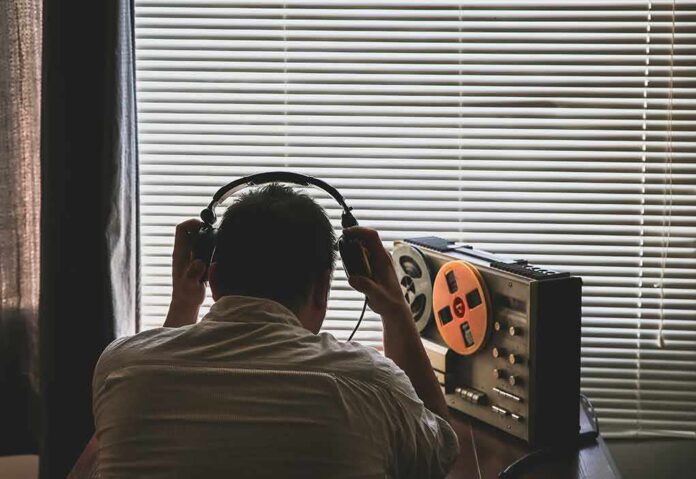Person wearing headphones listening to a reel-to-reel tape recorder