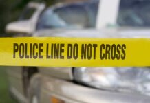 Yellow police tape reading POLICE LINE DO NOT CROSS in front of a vehicle