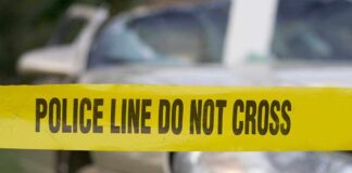 Yellow police tape reading POLICE LINE DO NOT CROSS in front of a vehicle