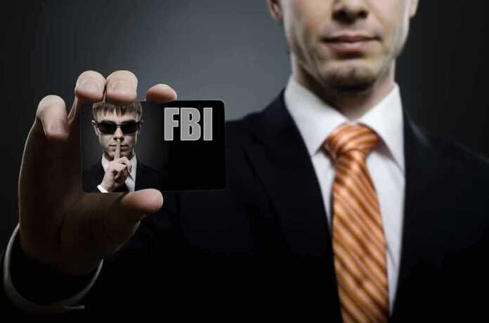 A man in a suit holding an FBI identification card while making a shushing gesture