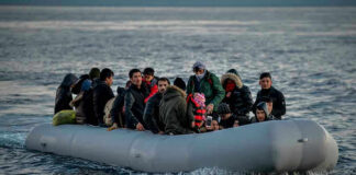 People on a packed raft in open water.