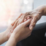 Young hands holding an elderly persons hand.