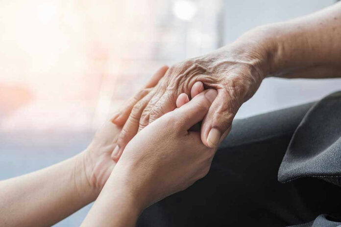 Young hands holding an elderly persons hand.