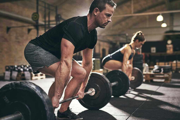 Man and woman lifting barbells in gym.
