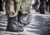 Row of soldiers in camouflage pants standing in formation with black boots