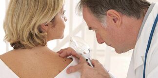 Doctor examining a patients skin with a magnifying glass