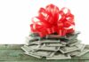 A stack of cash topped with a red ribbon bow