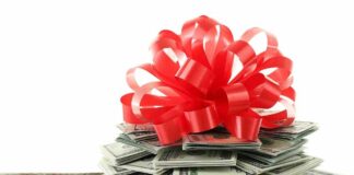 A stack of cash topped with a red ribbon bow