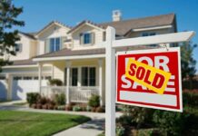 A house with a Sold sign in the front yard
