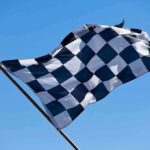 A checkered flag waving against a clear blue sky