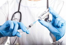 CDC SLASHES Vaccines – Health Crisis Looms Doctor filling syringe with vaccine from vial.