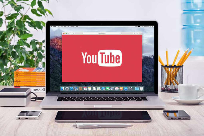 YouTube logo on a laptop screen on desk.
