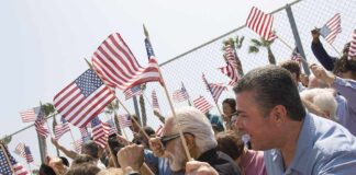 A diverse crowd holding American flags during a patriotic event