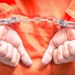 Hands in handcuffs wearing an orange jumpsuit