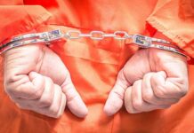 Hands in handcuffs wearing an orange jumpsuit