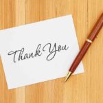 Parents Triumph in Cursive Education Showdown A thank you card with elegant handwriting next to a pen on a wooden table