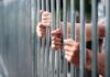Hands gripping metal prison bars
