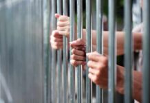 Hands gripping metal prison bars