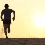 Silhouette of a man running on the beach during sunset