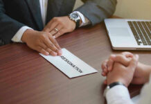 Handing in a resignation letter across a table.