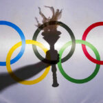 Miracle Repeat STUNS Canada — Then THIS Happened Shadow of torch over Olympic rings logo.