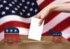 A hand placing a ballot into a box with political symbols on either side against a backdrop of the American flag