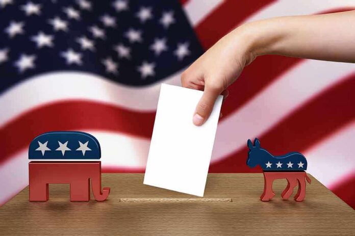 shutterstock_103487231.jpg A hand placing a ballot into a box with political symbols on either side against a backdrop of the American flag