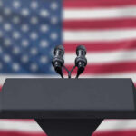 Trump’s 2028 ‘Dream Team’ Sparks GOP Buzz Podium with microphones, American flag background.