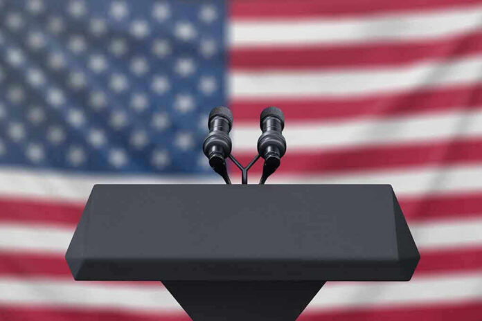 1223942521 Podium with microphones, American flag background.