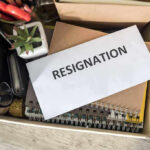 Woke Mayor Announces RESIGNATION Just Months After Swearing In Envelope labeled RESIGNATION atop office supplies in box.