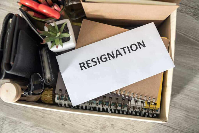 Envelope labeled RESIGNATION atop office supplies in box.