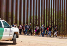 Chinese Nationals in Camo BUSTED At Border! People walking beside tall fence and border patrol vehicle.