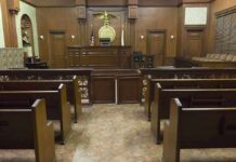 ICE Fills Court: 82 Judges in Blitz Hire! Interior view of an empty courtroom with wooden benches and a judges bench