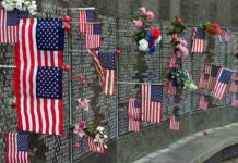 Memorial wall adorned with American flags and flowers
