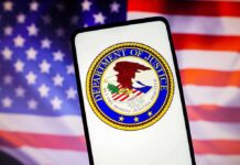 Department of Justice emblem displayed on a smartphone with an American flag background