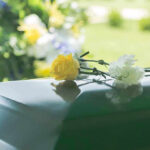 212 DEAD – Devastating Heatwave Worsens! Flowers on a closed casket at a funeral.