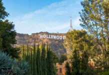 Hollywood Star MURDERED – Girlfriends Kid ARRESTED! Hollywood sign on hill surrounded by trees and buildings.