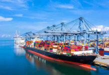 Iran Immediately Shuts Strait AGAIN – They Are Fuming! Container ship docked at a busy industrial port.